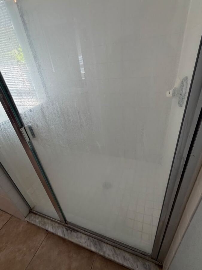Glass shower door before Loopera Group cleaning
